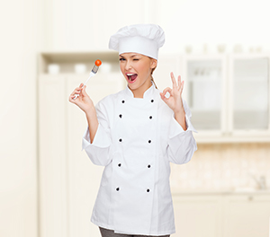 smiling female chef with fork and tomato
