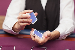 Dealer shuffling deck of cards while sitting at table of a casino entertainment industry with Carpal Tunnel
