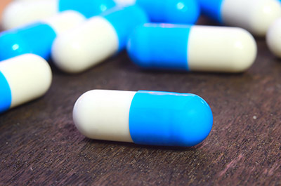 medicine capsule pill on wood background complications are high for those that seek CTS pain relief with prolonged oral pain medication regimens