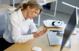 Woman dealing with finger pain and numbness while using computer