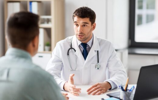 Doctor in a white coat talking with a patient during an office visit.