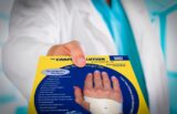 Doctor holding a Carpal Solution package showing a hand brace.