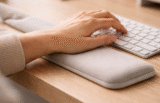 Hand typing on keyboard with cushioned wrist support pad.