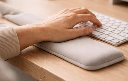Hand typing on keyboard with cushioned wrist support pad.