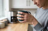 Woman holding a mug in a kitchen with hand discomfort linked to carpal tunnel syndrome