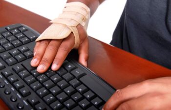 Hand wearing a carpal tunnel brace while using a computer keyboard